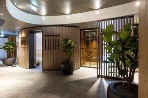 A modern lobby with a curved ceiling, wooden paneling, and large potted plants.