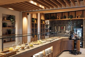 A buffet setup with various food items and a coffee machine. - Almwellness Hotel Pierer (Fladnitz an der Teichalm)