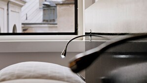 A window with a view of a building with a dome and a cross, a bed, and a pair of glasses on the windowsill. - Alma Boutique Hotel (Vienna)
