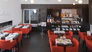 A restaurant with red chairs and tables, a bar area with various bottles, and a modern interior design. - Alma Boutique Hotel (Vienna)