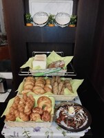 Uma mesa de buffet com diversos produtos de panificação, incluindo pão, croissants e doces.
