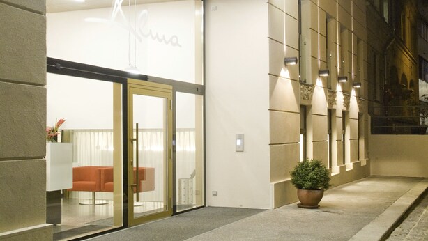 A hotel entrance with a glass door, a reception desk, and a seating area inside. - Alma Boutique Hotel (Vienna)