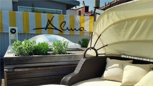 A sunbed with a canopy, a wooden bench, and potted plants. - Alma Boutique Hotel (Vienna)
