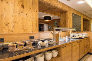 A buffet area with various food options and a chalkboard menu. - Hotel Alpenkönigin Alpine Luxury   (See)