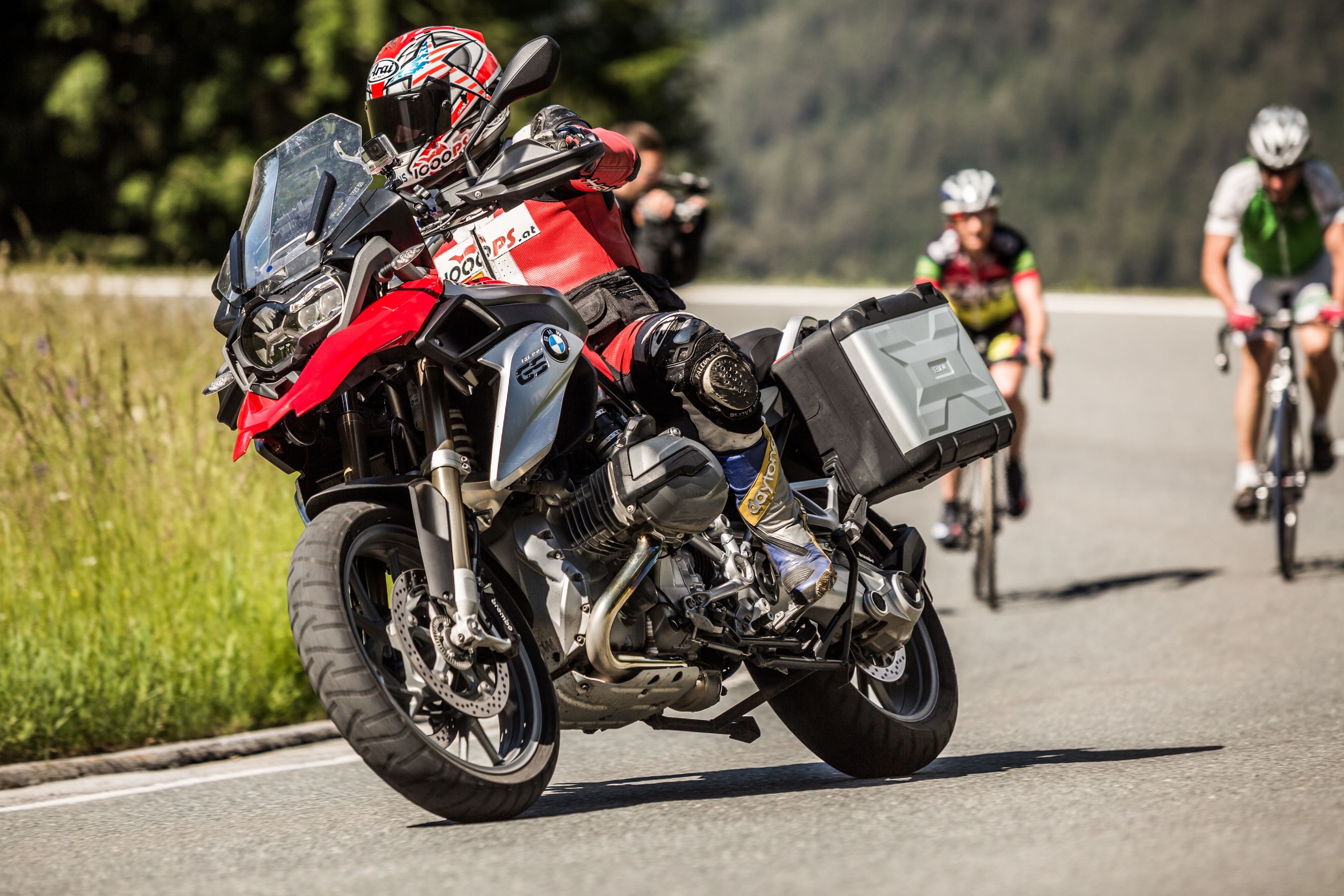 A motorcycle with a side box and a rider in red and white gear.