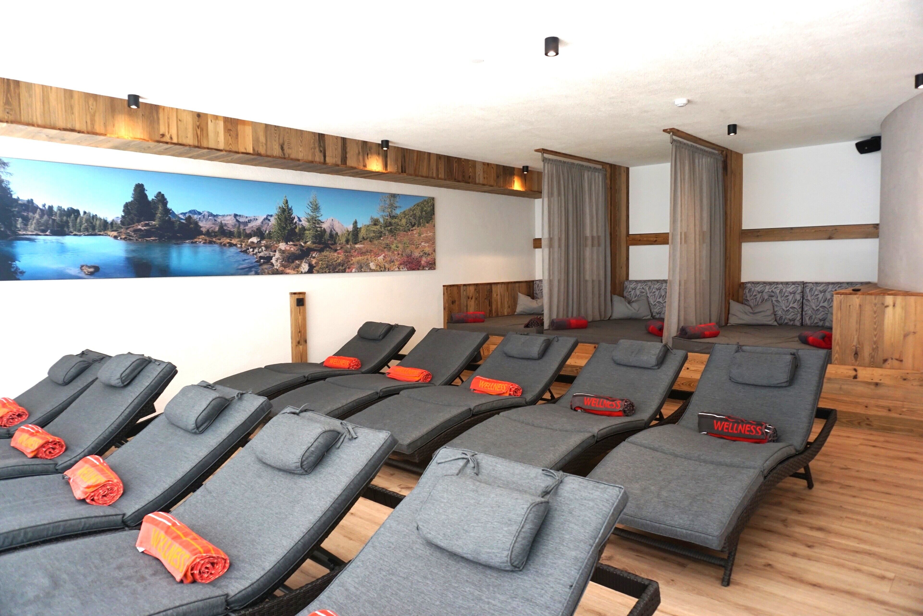A wellness room with multiple massage chairs, a large scenic wall mural, and wooden paneling.