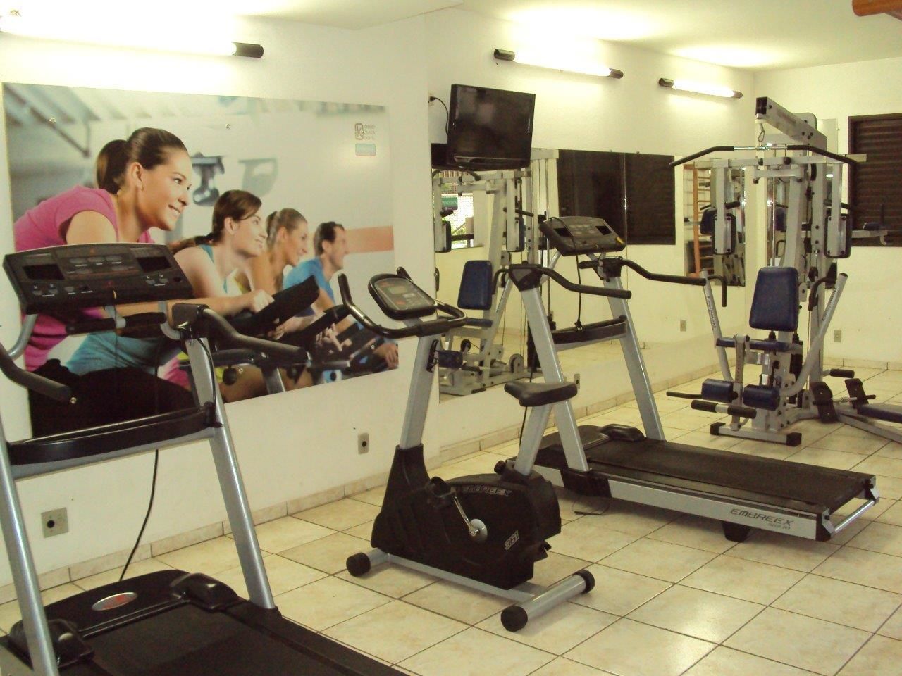 Academia com esteiras, bicicletas ergométricas e aparelhos de musculação.