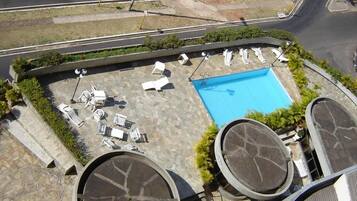 Una piscina al aire libre, sombrillas, sillones reclinables de piscina
