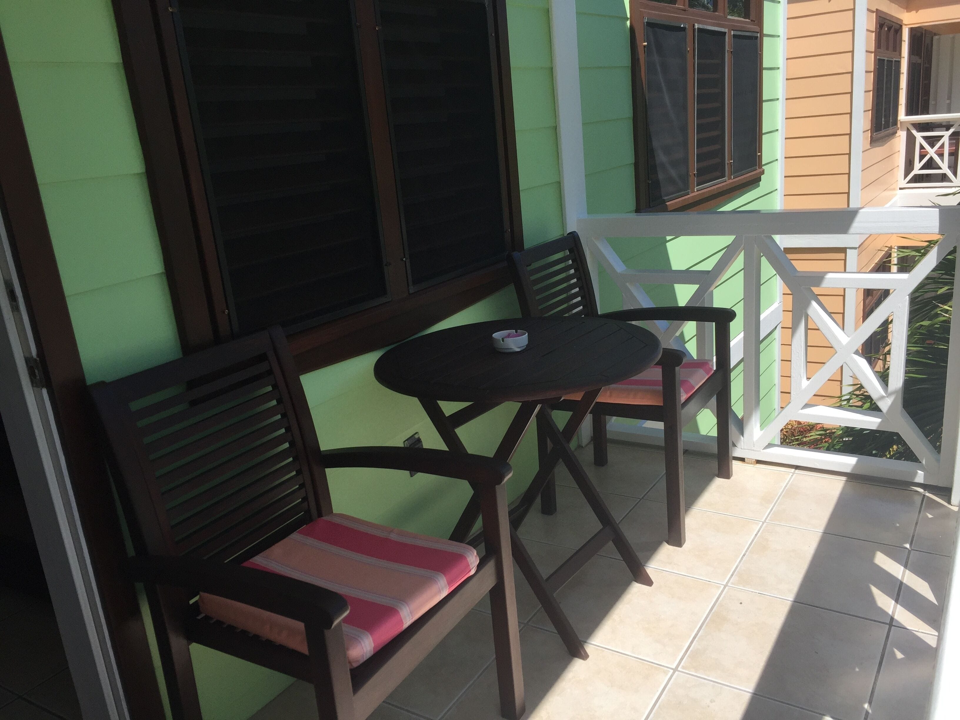 A small patio with a round table and two wooden chairs with cushions.