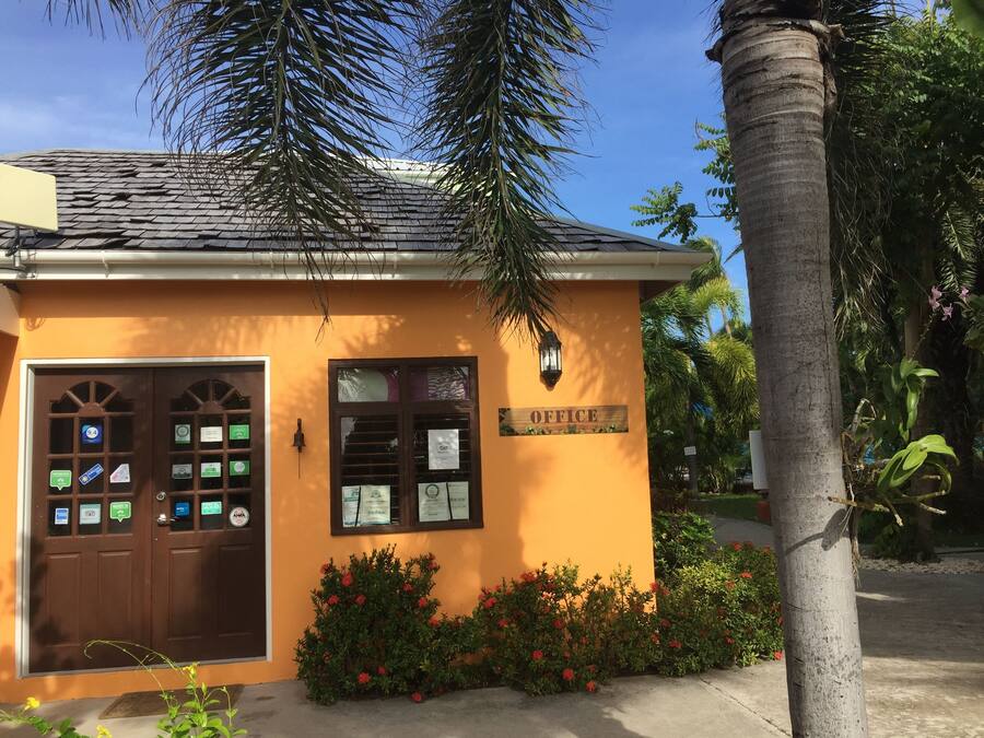 Un petit bâtiment avec une enseigne indiquant « BUREAU » sur la façade. Plusieurs certificats sont affichés aux fenêtres, et une porte porte une indication mentionnant une note de 9,4.