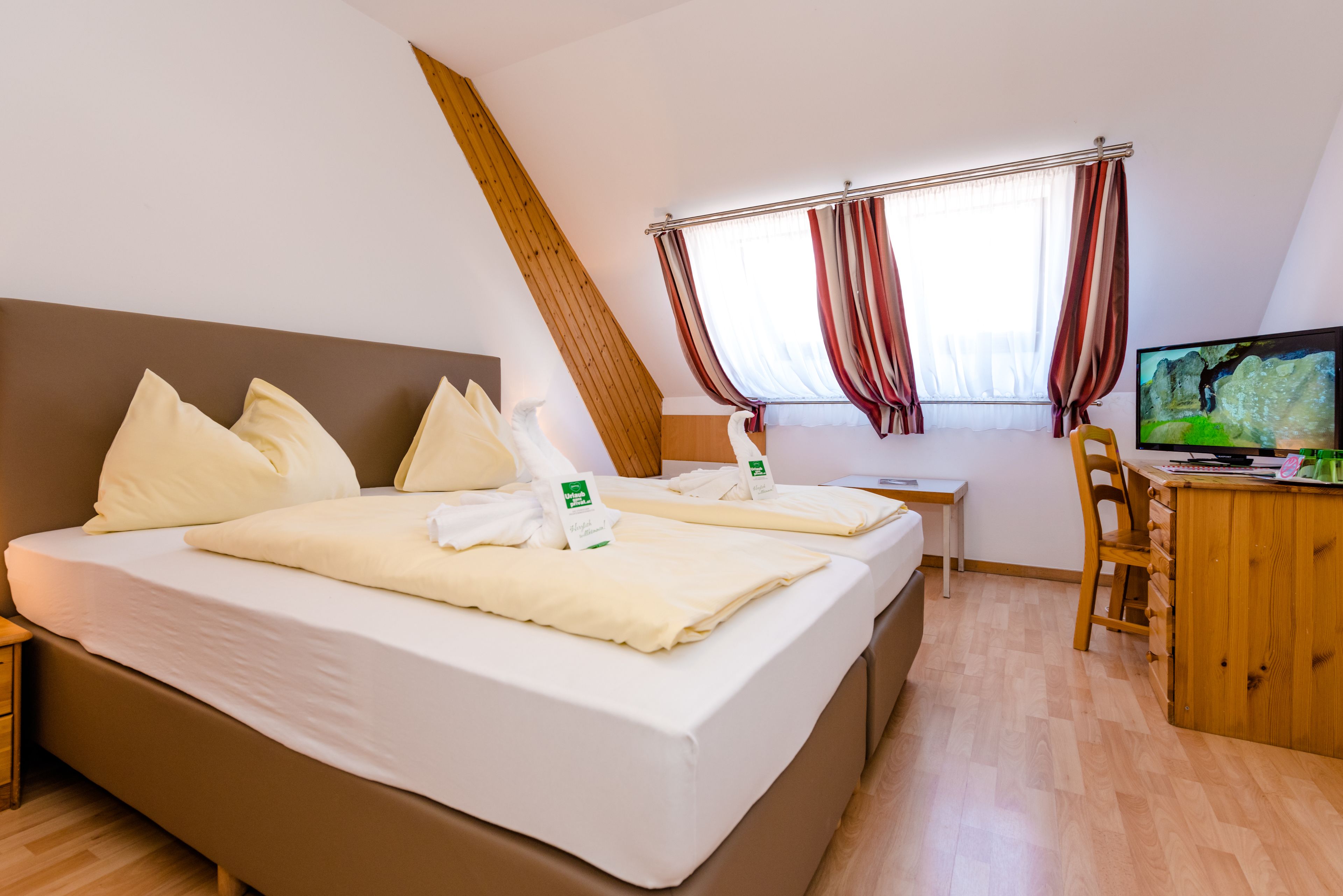 A hotel room with a large bed, a desk, a chair, and a television.