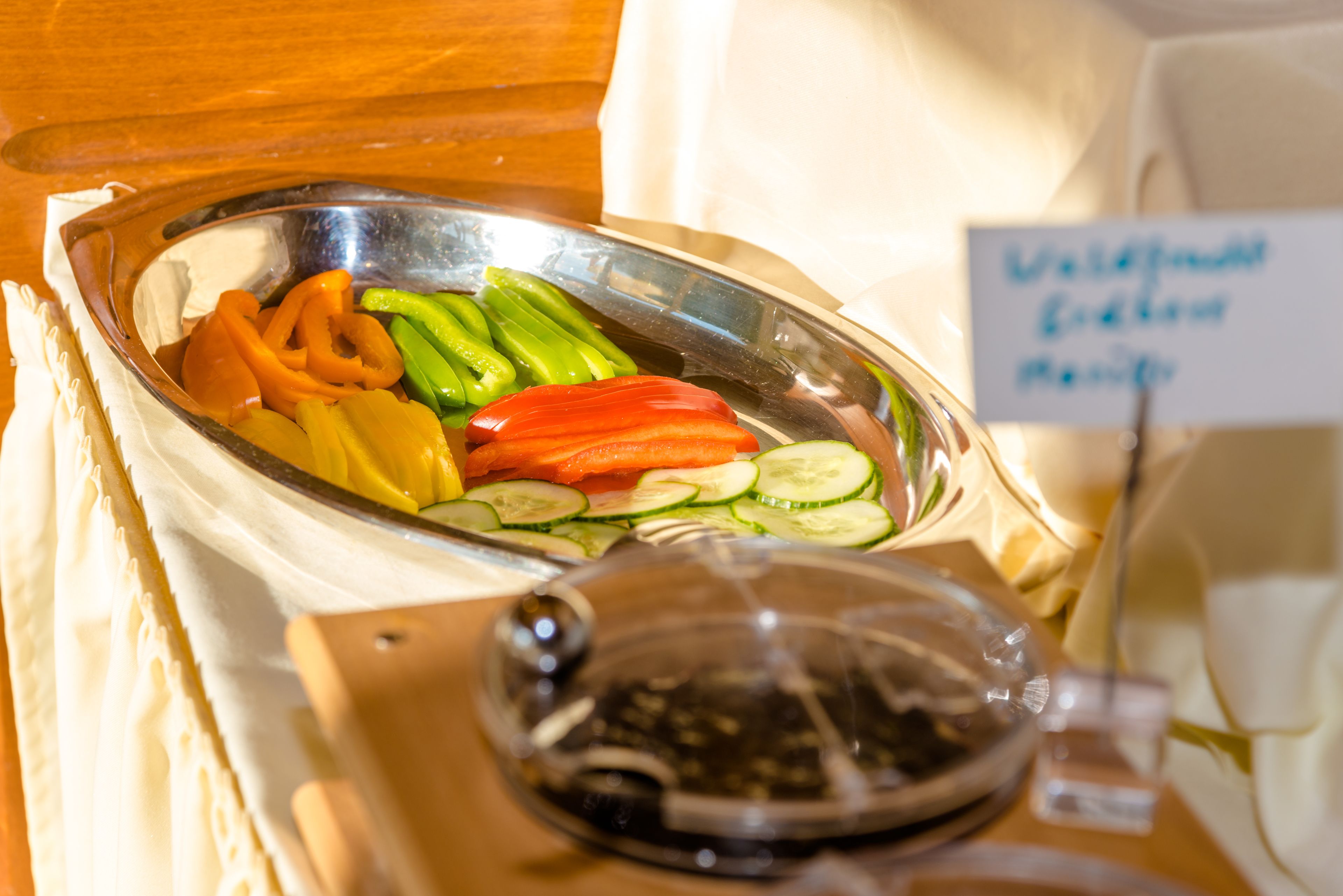 Un bufé con diferentes verduras y un cartel que indica el tipo de cocina.