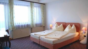 Un letto matrimoniale con due cuscini, un comodino con una lampada e una finestra con tende.