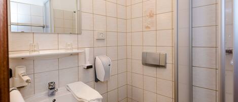 A modern bathroom with a sink, mirror, towel rack, and toilet.