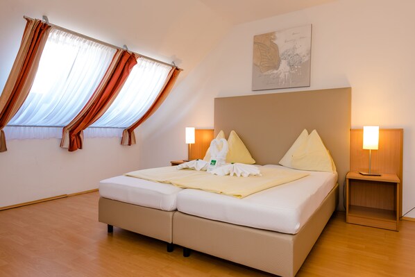 Habitación de hotel con cama, dos lámparas de noche, una ventana con cortinas y un cuadro en la pared.