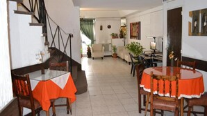 Un comedor con una escalera, un sofá y una mesa con mantel rojo.