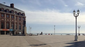 Una amplia plaza pública con un gran edificio que presenta ventanas arqueadas y una estatua.