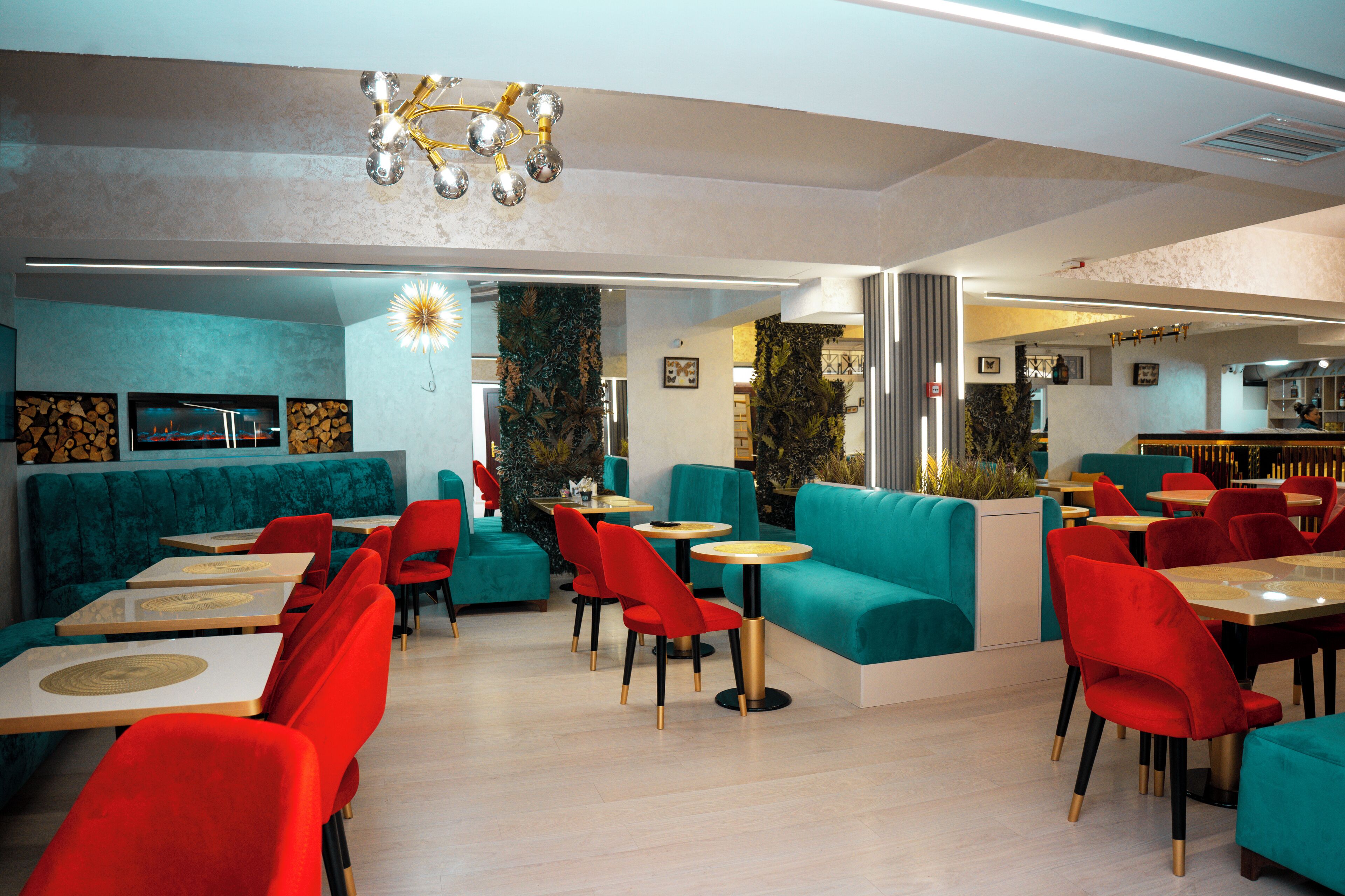 Un restaurant amb seients daurats i vermells, taules de fusta i un llumfer modern.