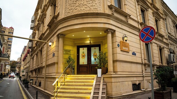 Ingresso di un hotel con una scalinata, un segnale di divieto di parcheggio e una targa con il nome dell'hotel.