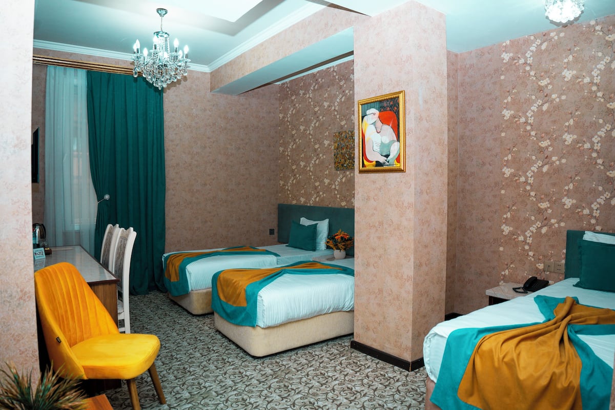 A hotel room with two beds, a desk, a chair, and a chandelier.