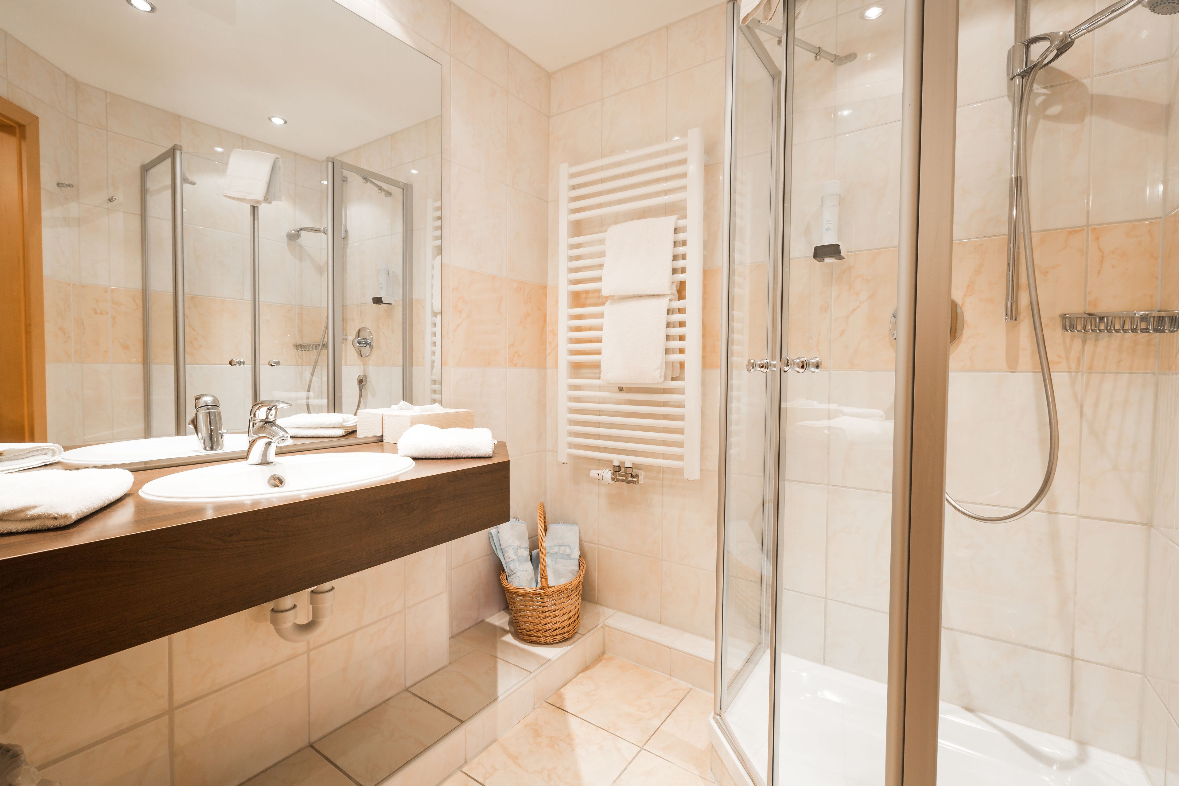 A modern bathroom with a glass-enclosed shower, a large mirror, and a wooden vanity with a sink.