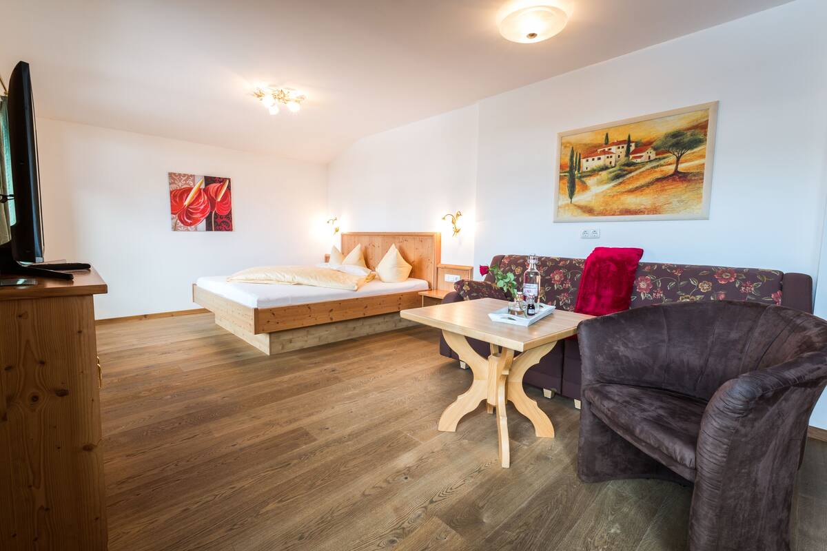 Um quarto com uma cama, um sofá, uma mesa e uma televisão.