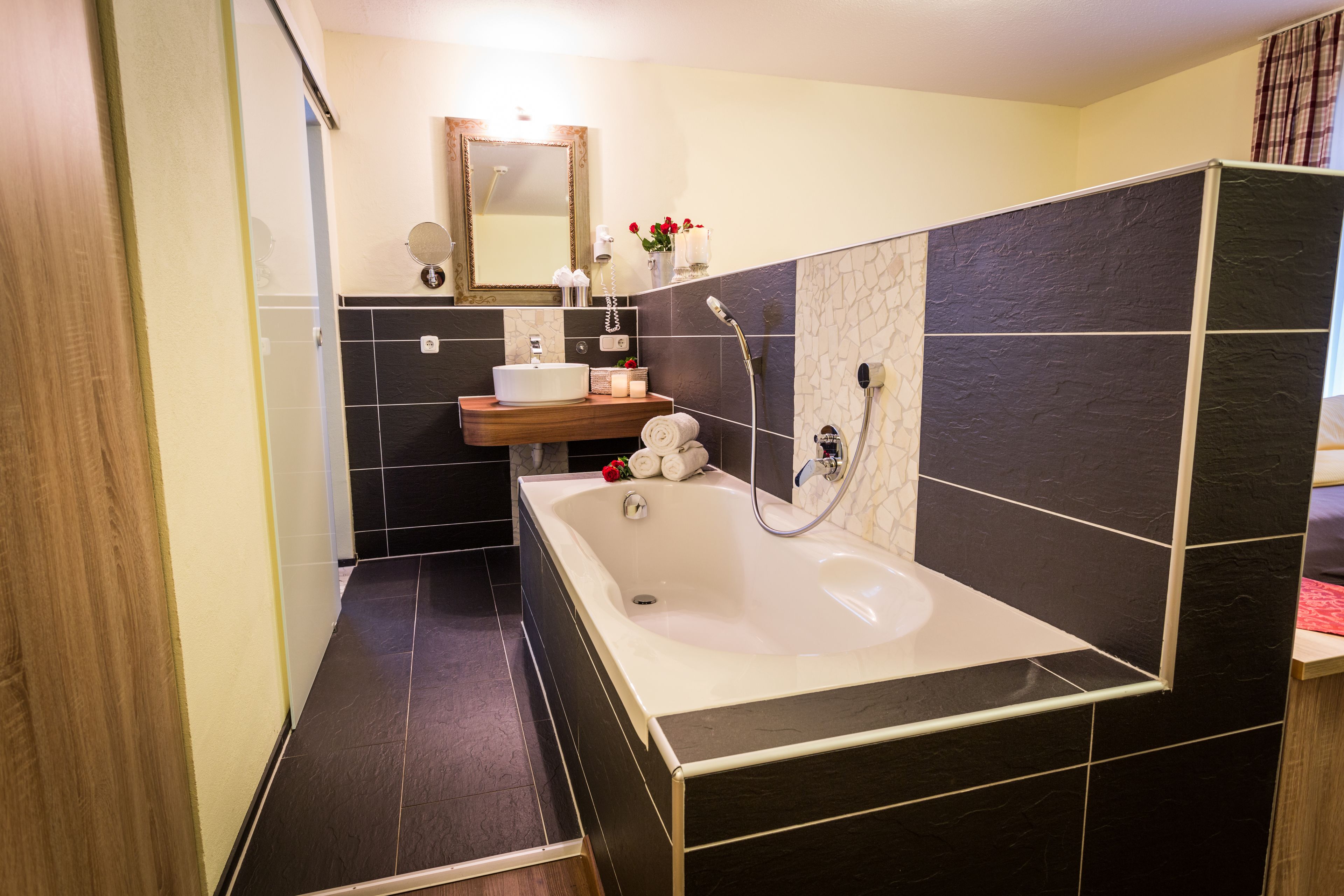 Een moderne badkamer met een vrijstaand bad, een wastafel met spiegel en een douchehoek.