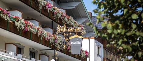A hotel with multiple balconies adorned with flowers and a sign indicating it is a post hotel.