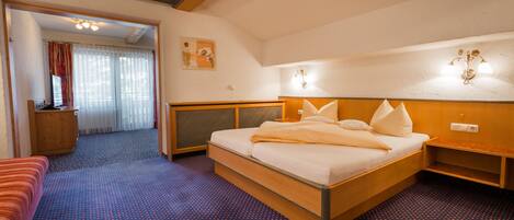 A hotel room with a large bed, a wooden headboard, a bedside table, and a small seating area.