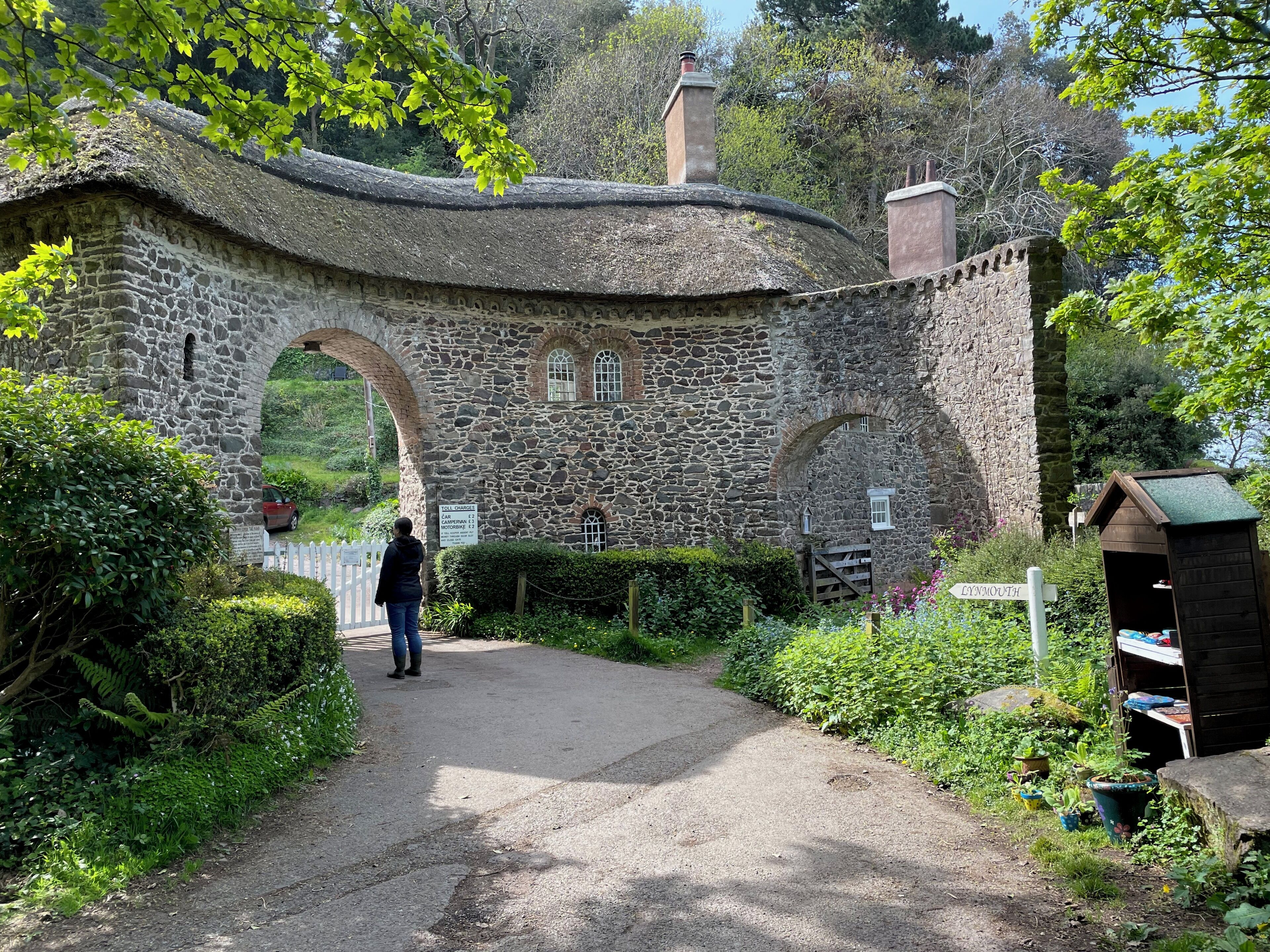 A stone archway leading to a building with a sign indicating toll charges.