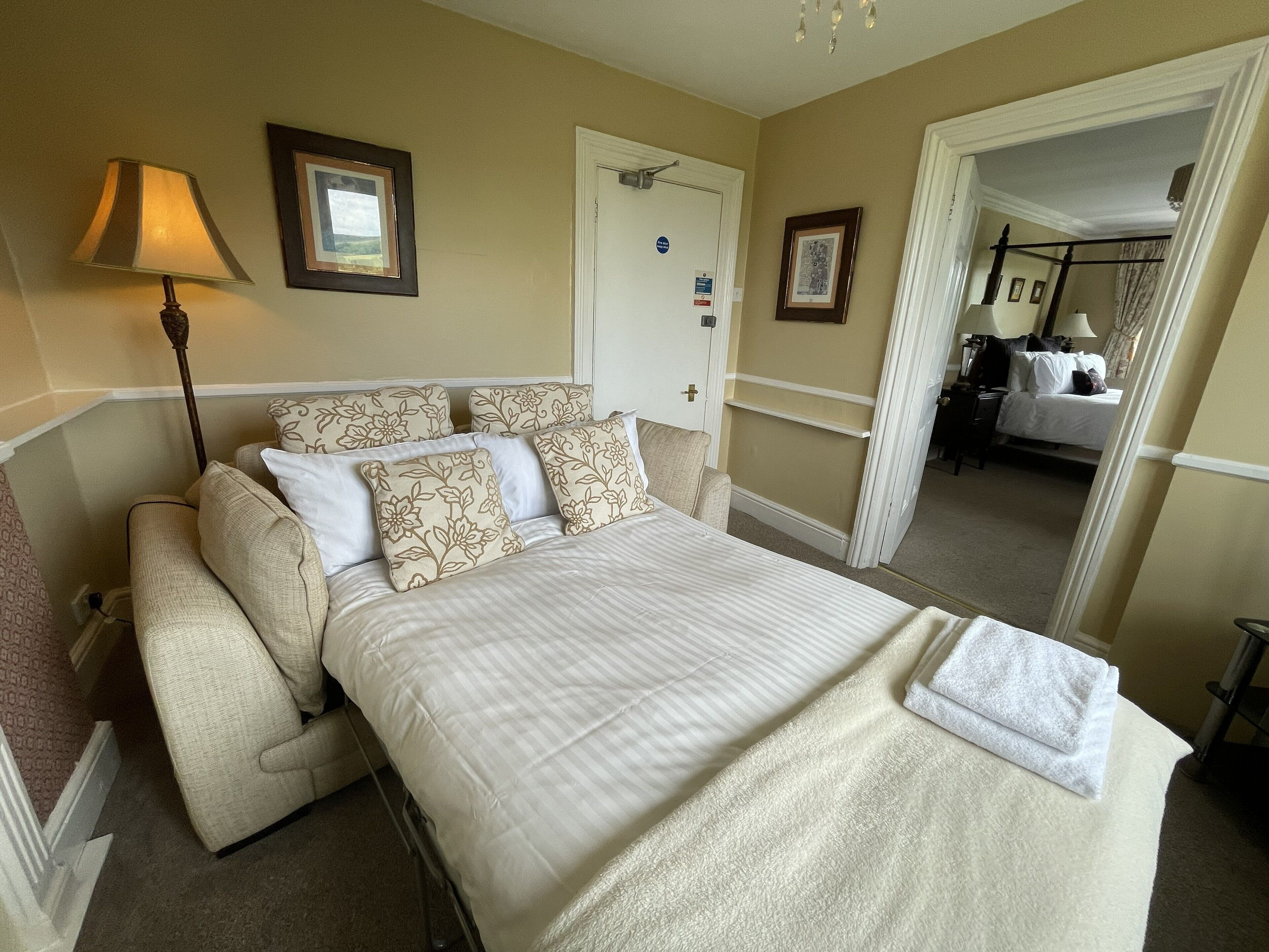 Une chambre d’hôtel avec un lit, une lampe de chevet, une porte et un miroir.
