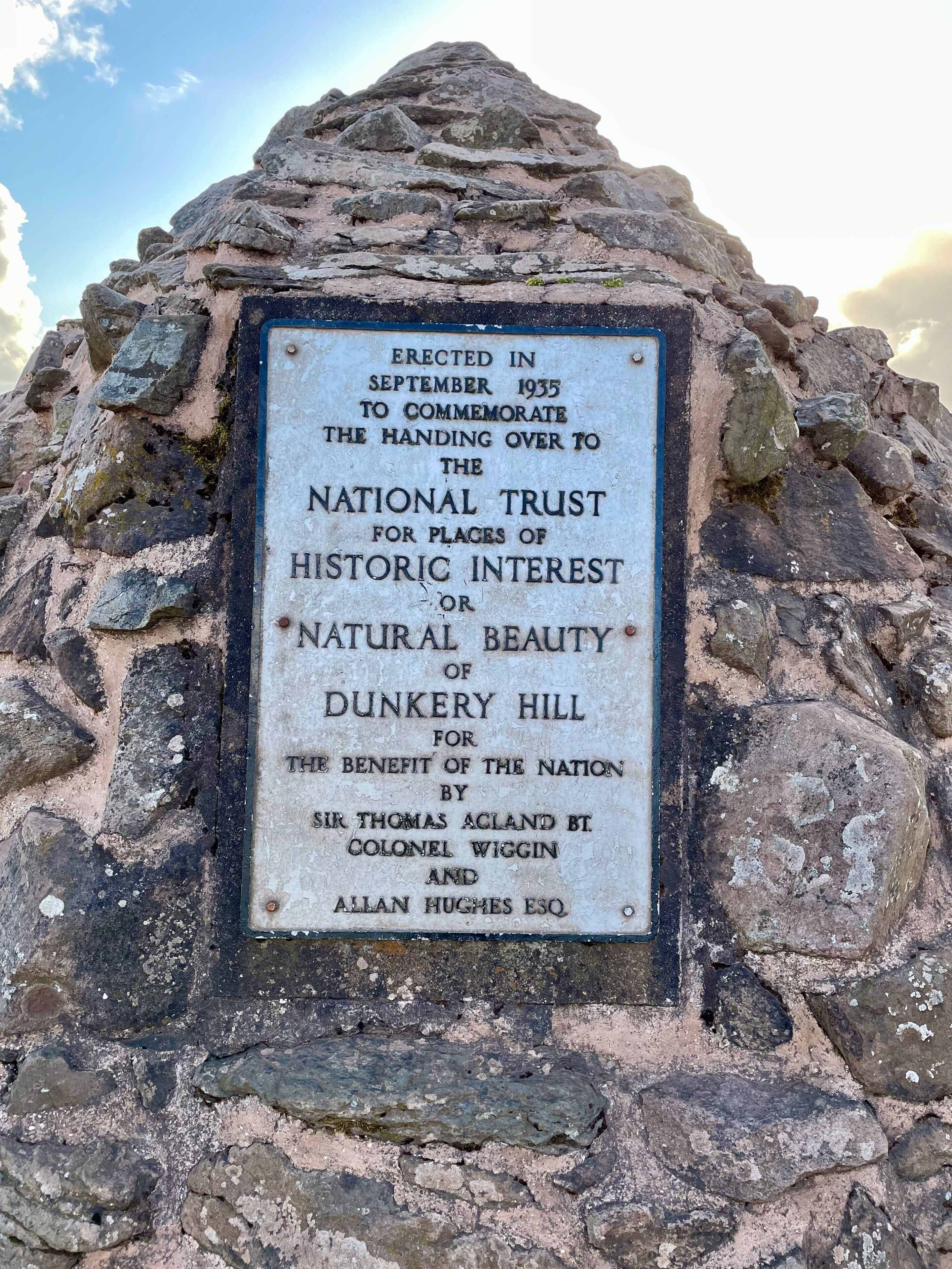 A weathered stone monument with an inscription commemorating the National Trust for places of historic interest or natural beauty.