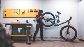 A workshop with a bicycle wheel mounted on a stand, tools on a pegboard, and a workbench.