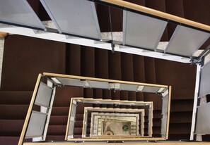 A spiral staircase with a wooden railing and a clock at the center.