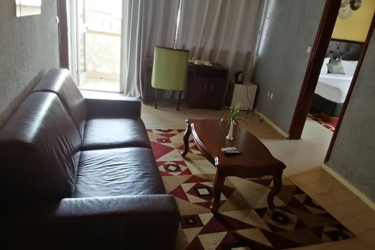 Una sala de estar con un sofá de cuero oscuro, una mesa de centro de madera y un tapete estampado.