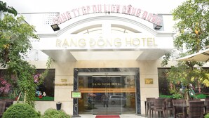 The entrance of Rang Dong Hotel with a clear glass facade, a red carpet, and outdoor seating area. - Rang Dong Hotel (Ho Chi Minh City)