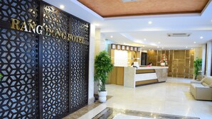 A hotel reception area with a modern design, including a reception desk, a large potted plant, and a seating area with a sofa. - Rang Dong Hotel (Ho Chi Minh City)