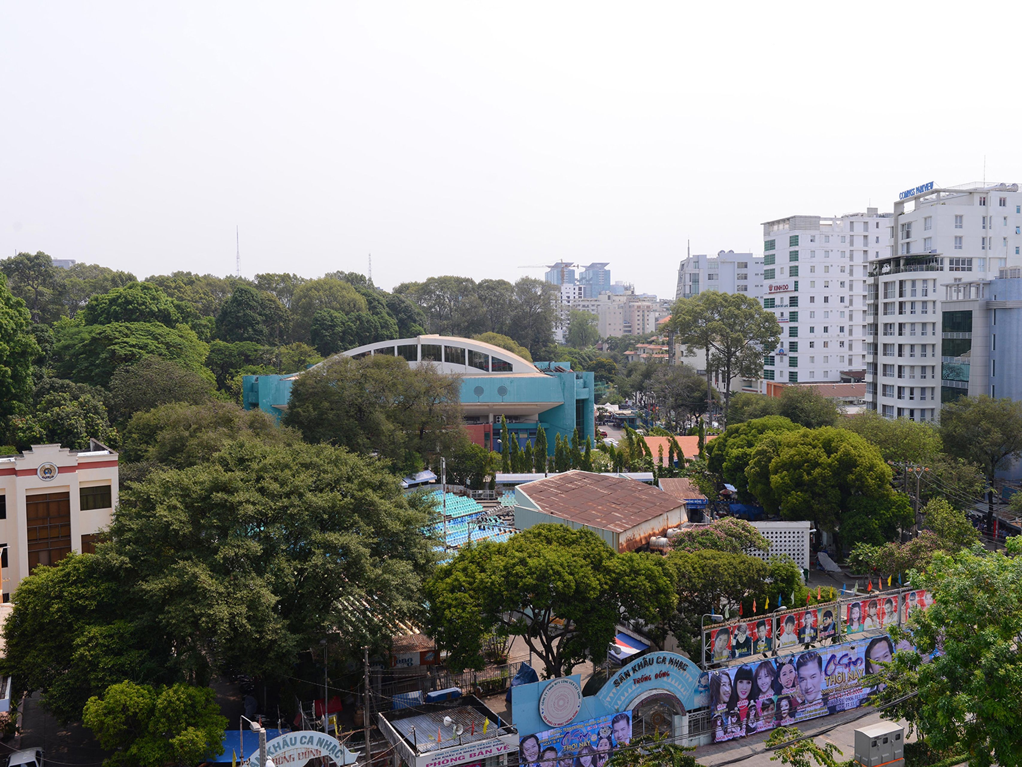 A cityscape with a prominent blue building surrounded by greenery and other buildings.