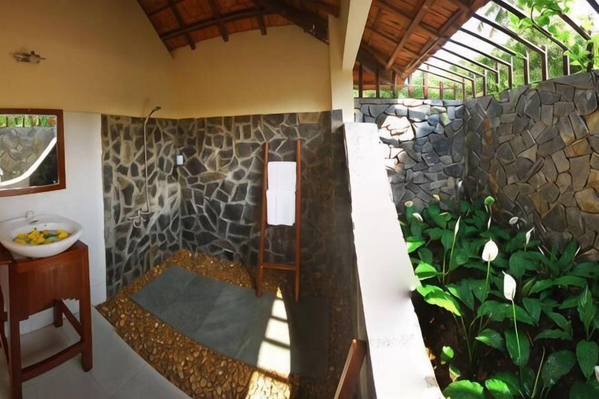 A room with a stone wall, a wooden bench, a small table with a bowl, and a whiteboard.