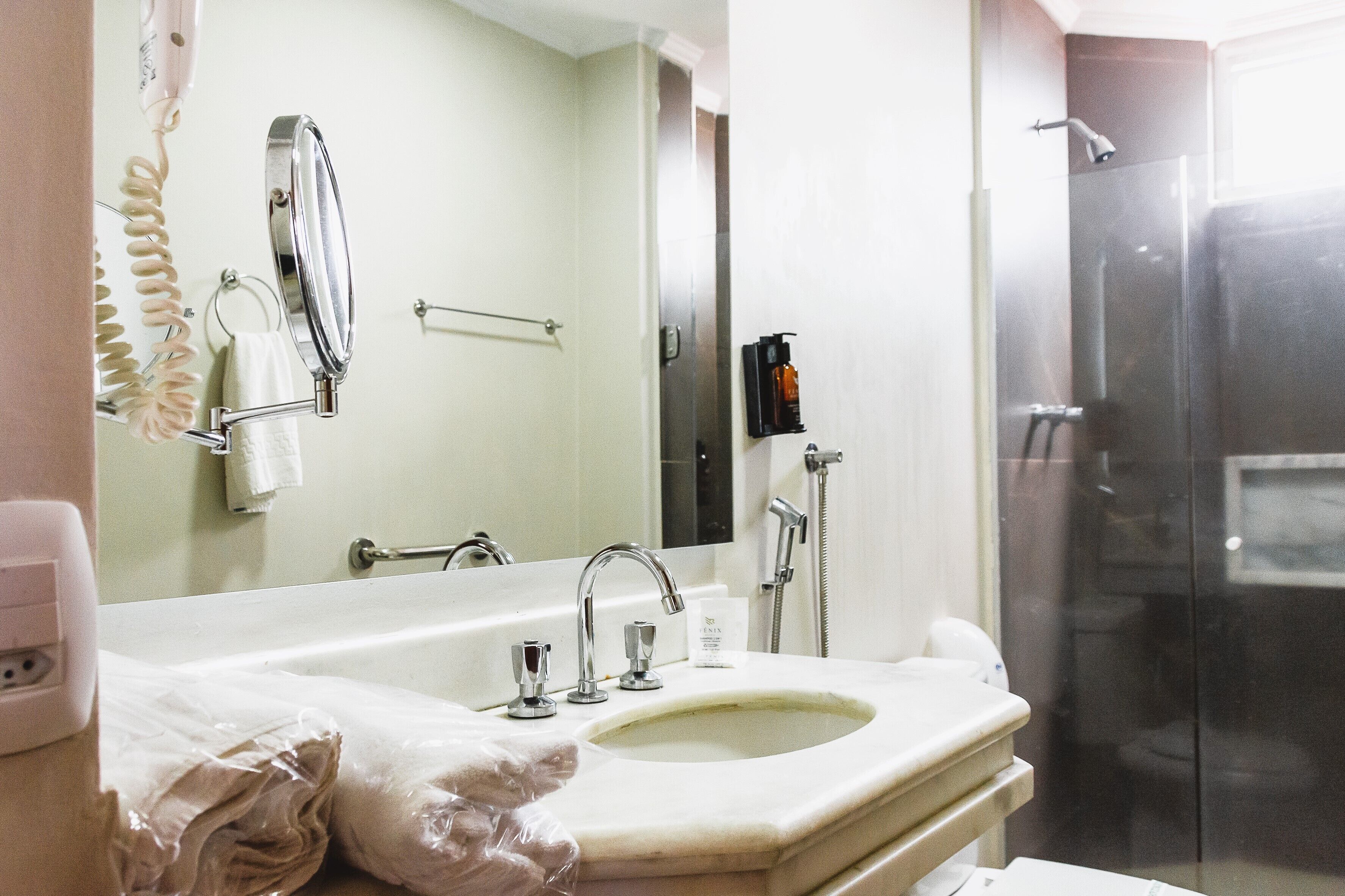 A bathroom with a sink, mirror, towel rack, and shower.