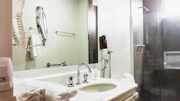 A bathroom with a sink, mirror, towel rack, and shower.