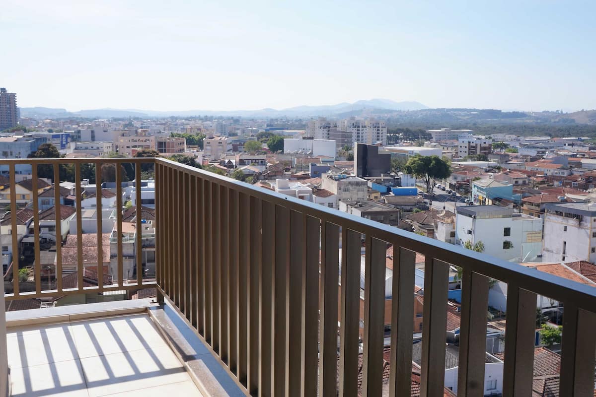 Un balcón con vista a un paisaje urbano, que incluye edificios y montañas a lo lejos.