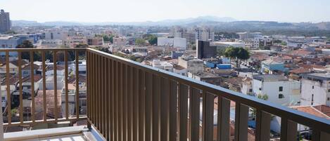 Un balcón con vista a un paisaje urbano, que incluye edificios y montañas a lo lejos.