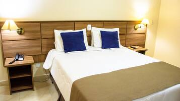 A hotel room with a bed, two bedside lamps, a bedside phone, and a nightstand.