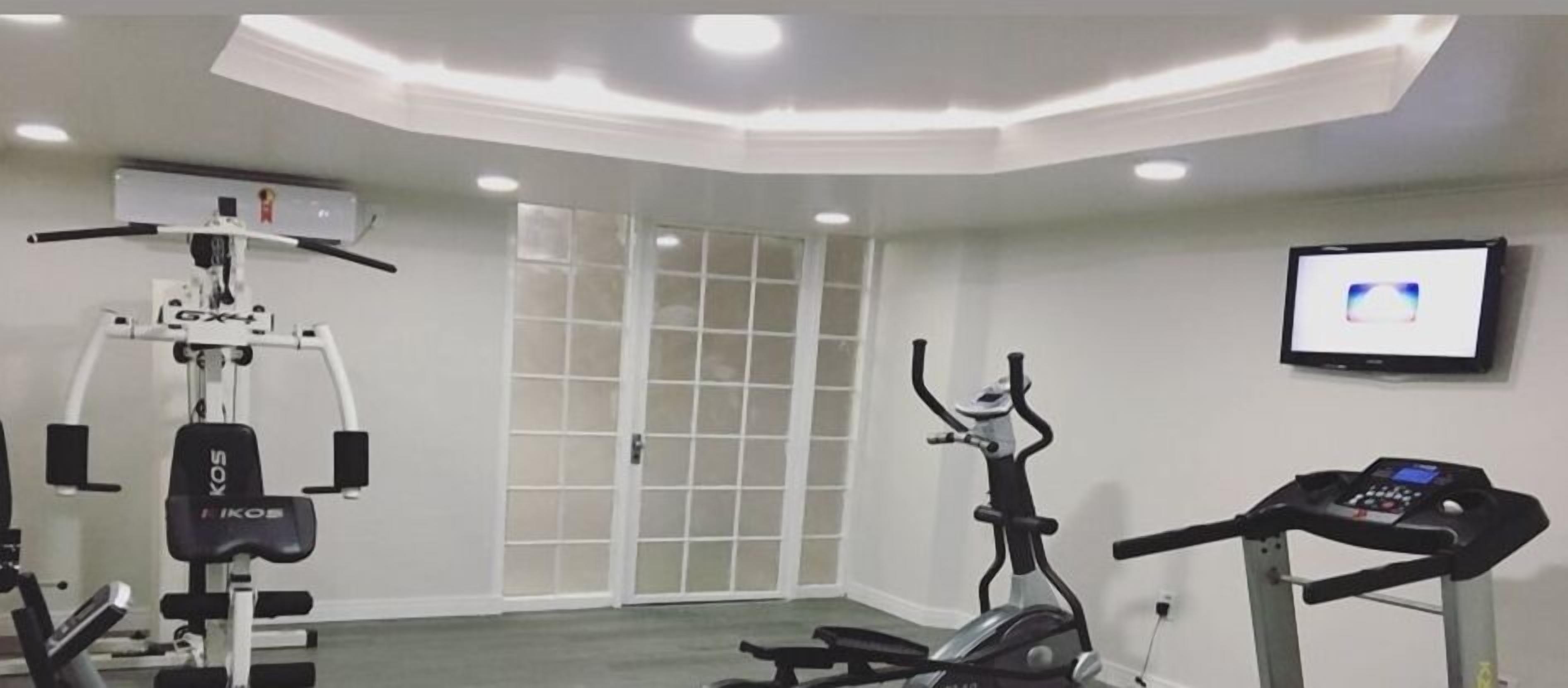 A gym with exercise equipment, a treadmill, and a wall-mounted TV.