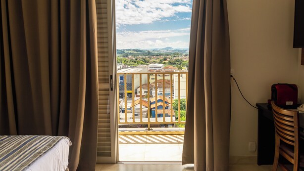 Una habitación de hotel con balcón, cama, escritorio y silla.