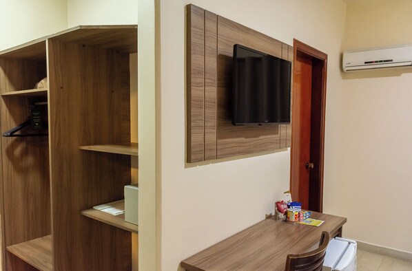 Una habitación con un armario de madera, un televisor montado y una mesita con aperitivos.