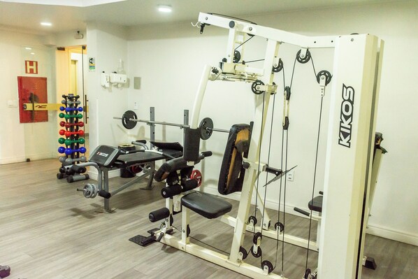 A gym with weightlifting equipment, a bench, and a squat rack.