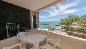 A balcony with a table and chairs, a view of the sea, and a tiled wall. - Apart Hotel Vespucci Residence (Natal)