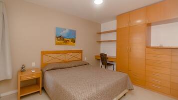 A bedroom with a bed, a desk, and a wardrobe.